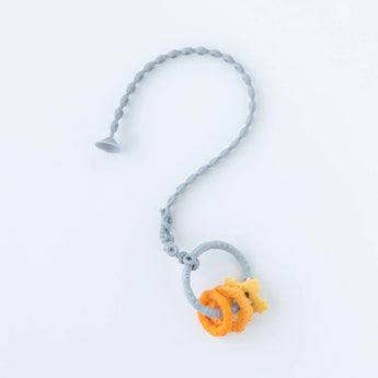 The Bumkins Silicone Accessory Tether in gray has star beads in orange and yellow, forming a question mark on white.