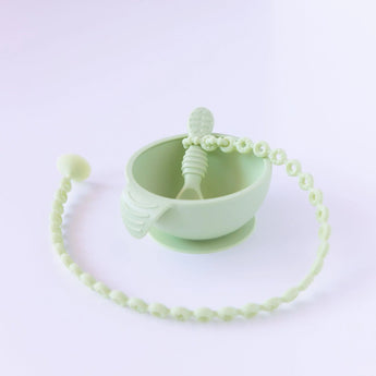 A mint-green baby feeding set by Bumkins, includes a suction bowl, spoon, and beaded pacifier clip in food-grade silicone.