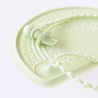 A light green Bumkins Silicone Accessory Tether 2-Pack in Sage with a plate, fork, and strap set against a white background.