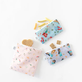 Three Bumkins reusable snack bags, featuring Disneys Princess Magic, Ariel, and Jasmine, filled with heart-shaped snacks on white.