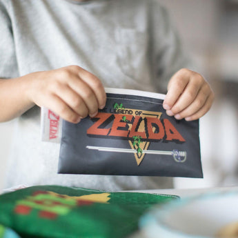 A child holds the Bumkins The Legend of Zelda™ reusable snack bags, cherishing them like a vintage game box.