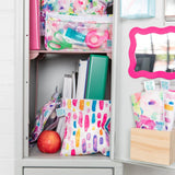 School locker with Bumkins durable zipper bags, books, an apple, and scissors. Plus a pink-framed mirror on the door.