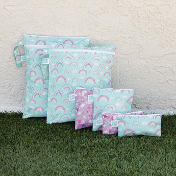 Seven Bumkins Wet Bag: Rainbows, in pastel colors with unicorn designs, crafted from waterproof fabric, rest on the grass.