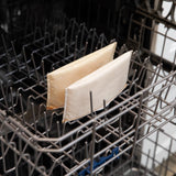 Two unused Bumkins reusable snack bags, Sunshine and Grounded, sit upright on a dishwashers bottom rack like face masks.