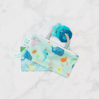 Two Bumkins Ocean Life & Whale Tail snack bags hold blue baby teething toys on a white surface.