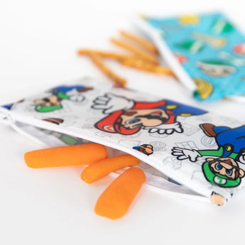 Two Super Mario™ reusable snack bags by Bumkins with carrots and pretzel sticks peeking out.