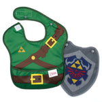 The Bumkins Caped SuperBib®: The Legend of Zelda™ Link resembles a fantasy adventure outfit with green tunic, belt, and emblem designs. Made from easy-wipe fabric for quick cleanups, it includes a gray shield-shaped accessory with a detailed crest.