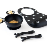 Cute black feeding set in food-safe silicone by Bumkins, with bowls, Mickey Mouse spoon, and a bib with a small white pattern.