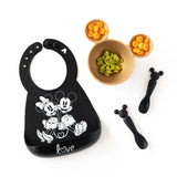 Black Mickey and Minnie bib, beige food-safe bowl with ears for avocado/carrot, and Bumkins black silicone Mickey dipping spoons.