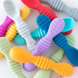 Bumkins Silicone Dipping Spoons in Gumdrop are playfully scattered on a white surface, perfect for little self-feeders.