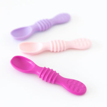 Three Bumkins Silicone Dipping Spoons in Lollipop colors, arranged diagonally on a white surface.