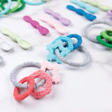 Bumkins Silicone Teething Charms in Pink: Safe, textured rings and spoons enhance motor skills with vibrant shapes and colors.