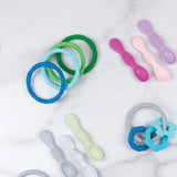 Bumkins Silicone Teething Rings 4 Pack: Summer in pastel shades soothe sore gums on a white marble surface. Food-safe and colorful.