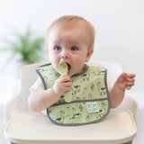 A baby in a green llama bib uses a Bumkins Silicone Dipping Spoon: Taffy, showcasing its first taste of independence.