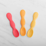 Bumkins Tutti-Frutti Silicone Dipping Spoons in red, orange, yellow lie on a white marble surface.