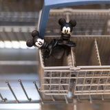 Two small, black Mickey Mouse Silicone Chewtensils® by Bumkins playfully perch in a dishwasher basket inspecting utensils.