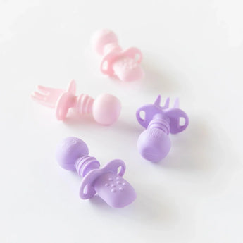 Three Bumkins Silicone Chewtensils® in pink/purple with sensory bumps sit on a white surface. Perfect for baby-led weaning.