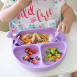 A child enjoys baby-led weaning from a purple divided plate, filled with pasta and veggies, using Bumkins Lavender Chewtensils®.