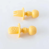 Bumkins Pineapple Silicone Chewtensils®: A yellow fork and teething spoon for babies, food-safe with handles, on a white background.