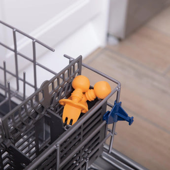 A Tangerine Bumkins Silicone Chewtensil® is placed in the dishwasher utensil basket; its 100% food-safe silicone.