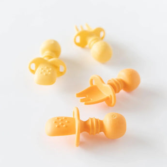 Four Silicone Chewtensils® in Tangerine by Bumkins, with fork and spoon ends, look like pacifiers, made of 100% food-safe silicone.