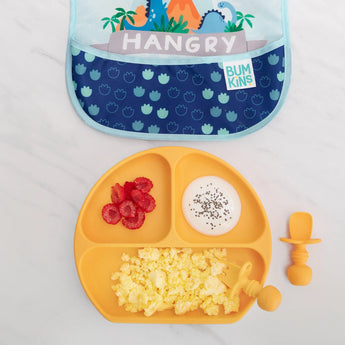 A childrens plate with scrambled eggs, raspberries, and yogurt with seeds sits beside Bumkins Tangerine Chewtensils®. Great for weaning.