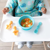 Child in high chair enjoys green star snacks with Bumkins colorful bib. Tangerine Silicone Chewtensils® ensure 100% food-safe silicone.