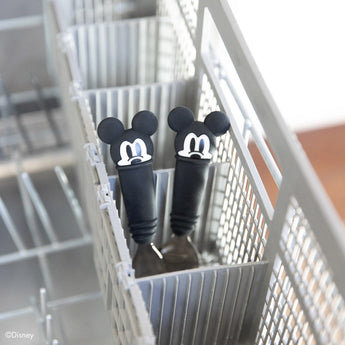 Two Bumkins Spoon + Fork with Mickey Mouse handles stand upright in the dishwashers cutlery basket.