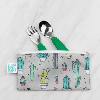 The Spoon + Fork: Jade by Bumkins is set on white marble, stored in a gray pouch with cactus prints.