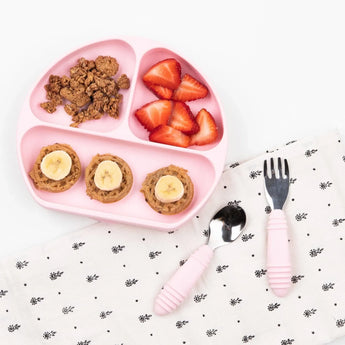 Pink baby plate with granola, strawberries, and bananas. Bumkins Spoon + Fork: Pink on napkin makes self-feeding fun.