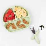 A divided round plate with watermelon, banana, mini waffles beside a Bumkins Spoon + Fork: Sage on a food-safe silicone mat.