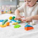 A child joyfully molds colorful clay on a Bumkins Splat Mat: Wander at the table.