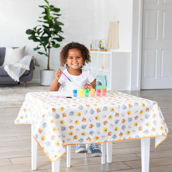 A child paints happily on a Bumkins Splat Mat: Winnie and Friends, ensuring easy spill and splash cleanup in the bright living room.