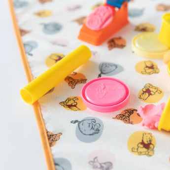 Close-up of colorful play-dough tools and shapes on Bumkins Splat Mat: Winnie and Friends, perfect for easy cleaning.