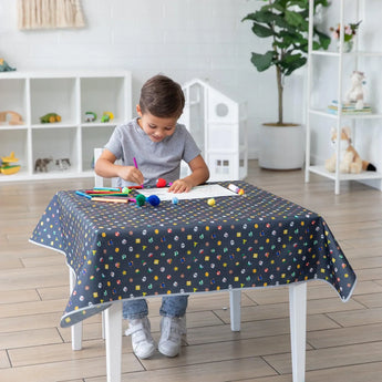 A child draws at a small table covered with the colorful, machine washable Bumkins Splat Mat: Super Mario™ Lineup.