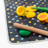 Colorful Splat Mat: Super Mario™ Lineup by Bumkins with a wooden rolling pin and open yellow containers of green & orange playdough.