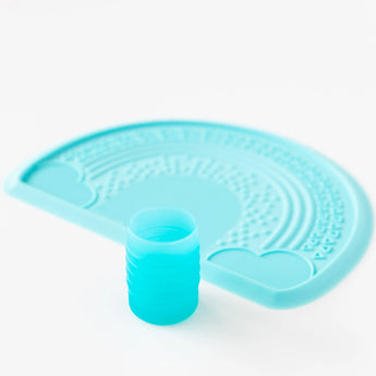 Bumkins Silicone Starter Cup: Blue on a placemat with textures, set against a white background.