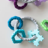 Bumkins Silicone Teething Charms in blue develop motor skills, made from food-safe silicone on a white surface.