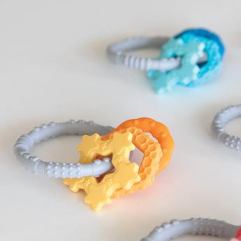 Bumkins Silicone Teething Charms offer soothing teething relief with yellow and orange star-shaped, food-safe silicon on a gray ring.