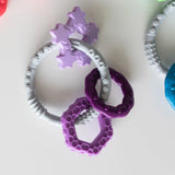 Bumkins Silicone Teething Charms in Purple offer colorful, textured teething relief against a pristine white backdrop.