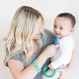 A woman smiles at a baby, wearing Bumkins Silicone Teething Rings 4 Pack: Summer made from food-safe silicone for soothing.