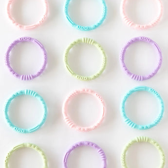 Four Bumkins Silicone Teething Rings in pastel shades, made of food-safe silicone, arranged to soothe sore gums.