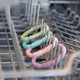 Bumkins Silicone Teething Rings 4 Pack: Spring are placed on a dishwasher rack, ready to soothe sore gums.