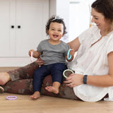 A child sits on a womans lap, smiling with Bumkins Silicone Teething Rings 4 Pack: Spring. Both are filled with joy.