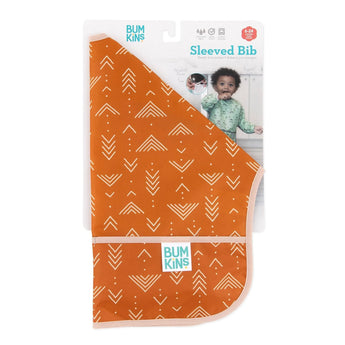 The Bumkins Sleeved Bib: Grounded, made from waterproof fabric with white geometric patterns, comes in packaging. A photo of a child wearing a similar Desert Boho bib shows its ideal for ages 6-24 months.