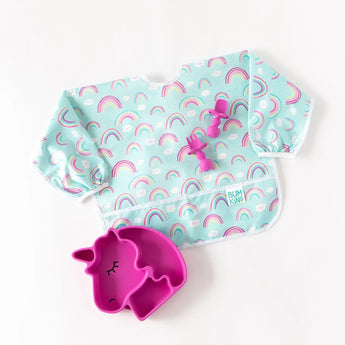 The Bumkins Sleeved Bib: Rainbows in pastel colors pairs perfectly with a pink unicorn-shaped bowl and matching fork and spoon set. Its stain and odor-resistant, waterproof fabric is ideal for easy cleanup, making it perfect for baby-led weaning.