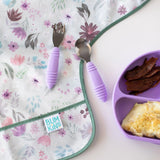 Bumkins Floral Sleeved Bib with purple utensils and lavender plate—ideal for baby-led weaning bacon and omelette meals.