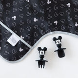 Bumkins Sleeved Bib in Mickey Mouse Icon B&W is waterproof and stain-resistant, paired with black mouse ear utensil set.