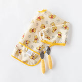 Bumkins Sleeved Bib Winnie Loves Hunny in yellow, with a baby spoon and fork set on white.