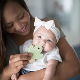 A smiling woman holds her baby, who finds teething relief with Bumkins fun Silicone Teether: Cactus.